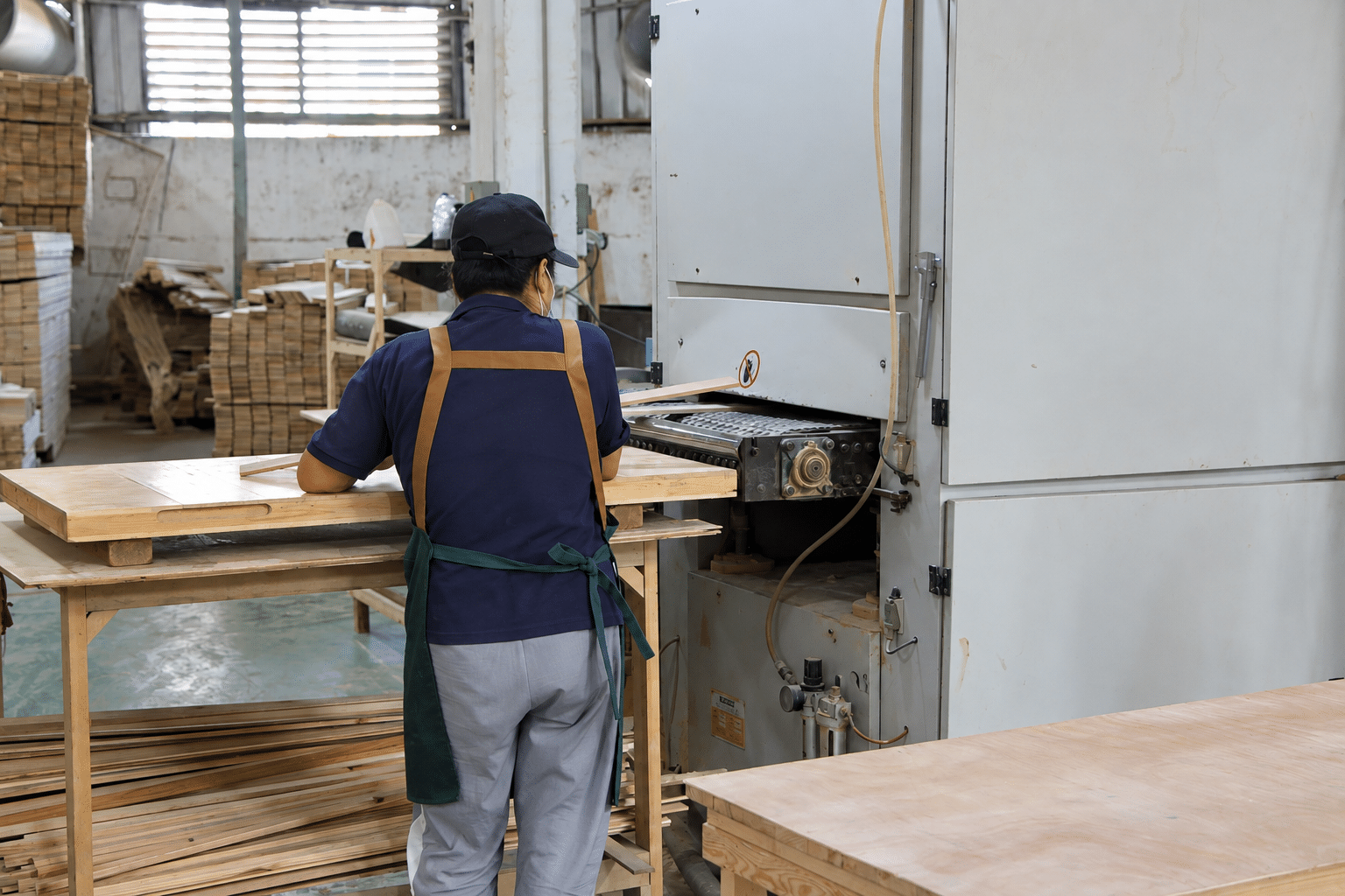 Bropool worker machining a wooden sauna panel beside production equipment