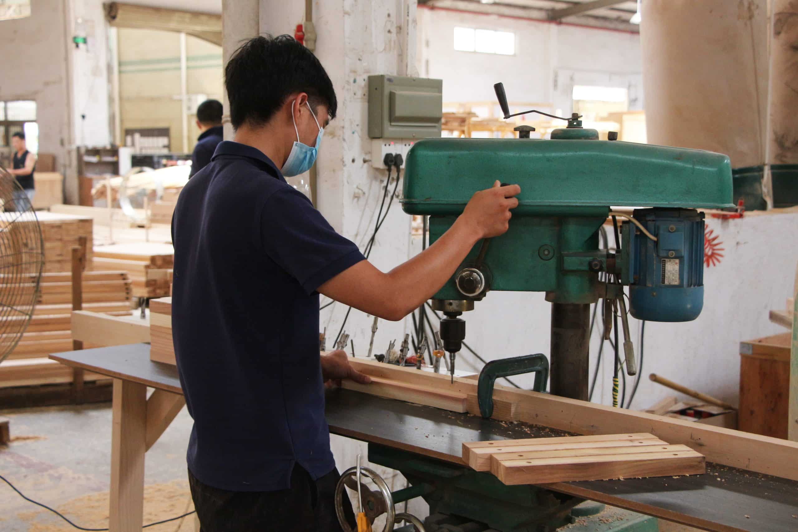 Bropool worker drilling a timber sauna component in the woodworking workshop
